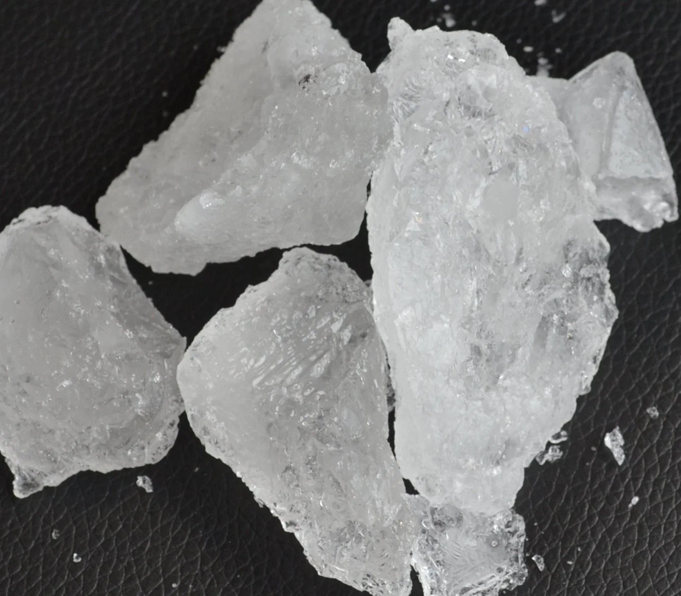Close-up translucent alum crystals scattered on dark surface